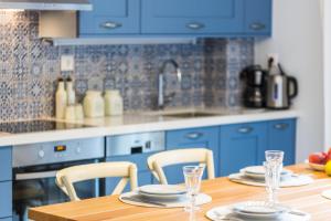 a kitchen with blue cabinets and a wooden table with chairs at Philoxenia Villas in Panormos Rethymno