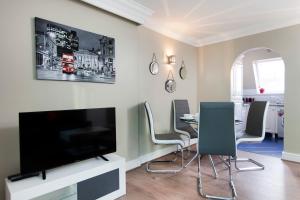 un soggiorno con TV e tavolo con sedie di 2Bed 2Bath Apartment in Fitzrovia - FREE Exclusive Parking a Londra