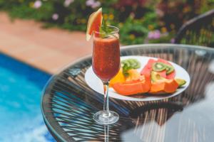 a drink sitting on a table with a plate of fruit at Palmeiras Guest House Maputo in Maputo