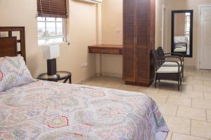 a bedroom with a bed and a desk and chairs at Timbo's Apartelle in Roseau