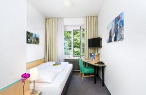 a hotel room with a bed and a desk at Hotel am Hofgarten in Düsseldorf