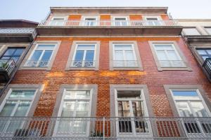 a red brick building with white windows and a balcony at Oporto Mezzanine - by ML Apartments in Porto