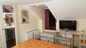 a small room with a bed and a flat screen tv at L'Amphitryon in Coudray