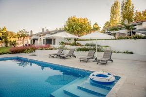 a swimming pool with two chairs and an umbrella at Pleiades Boutique Villas in Kriopigi