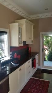 a kitchen with white cabinets and a sink and a window at Matai Huka Boutique Accommodation in Paraparaumu