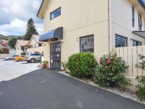 a building with a car parked in a parking lot at Bella Vista Motel Dunedin in Dunedin