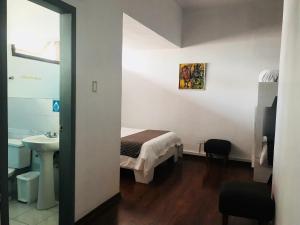 una camera da letto con un letto e un lavandino in una stanza di Hostal Posada del Maple a Quito