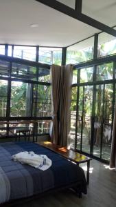 a bedroom with a bed and a large window at Bann Rai Klai Weang Homestay in Ban Muang Chum