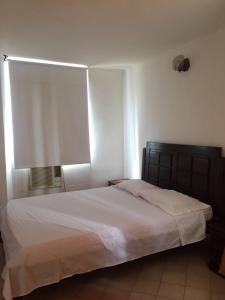 1 dormitorio con 1 cama grande con sábanas blancas y ventana en Conjunto Residencial la Mansion, en Santa Marta