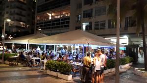 un grupo de personas sentadas en mesas bajo un paraguas en Loft Copacabana Avenida Atlantica en Río de Janeiro