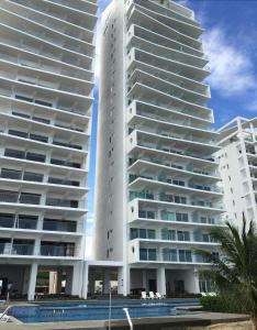 dos altos edificios blancos con una piscina frente a ellos en Suite frente al mar, en Tonsupa