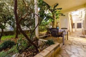 une terrasse avec une table, des chaises et des arbres dans l'établissement Apartments Vinko, à Trogir