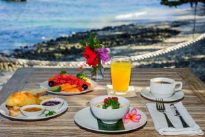 een tafel met borden en een glas sinaasappelsap bij Hai Tide Beach Resort in Nusa Lembongan