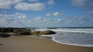 una spiaggia con rocce e l'oceano in una giornata nuvolosa di Los Nogales a Punta Del Diablo Altre 4 foto