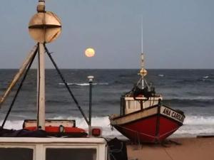 una barca seduta sulla spiaggia vicino all'oceano di Los Nogales a Punta Del Diablo