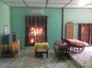 Pokój z łóżkiem, telewizorem i krzesłami w obiekcie Time 2 Resort w mieście Pai