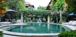 a swimming pool in the middle of a yard at Kusnadi Hotel in Legian