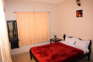 1 dormitorio con 1 cama con manta roja y ventana en SkyHighVilla, en Kodaikanal