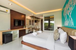 a bedroom with a white bed and a television at River Front Krabi Hotel in Krabi