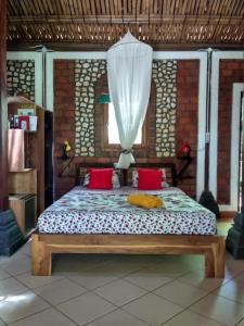 a bedroom with a bed with red pillows and a curtain at Villa Tentrem in Kemadang