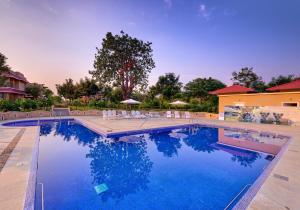 a large swimming pool with chairs and a house at Sterling Kanha in Kānha