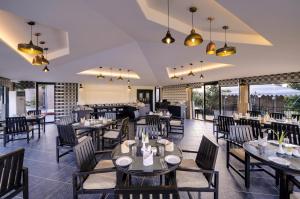un restaurante con mesas, sillas y ventanas en Sterling Kanha en Kānha