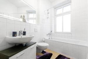 a white bathroom with a sink and a toilet and a tub at Grand Central Mitte Apartment in Berlin