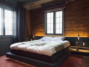 a large bed in a room with two windows at Tollboden Hotell - Unike Hoteller in Kragerø