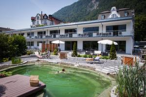 a person swimming in a pool in front of a hotel at Carlton-Europe Vintage Adults Hotel in Interlaken