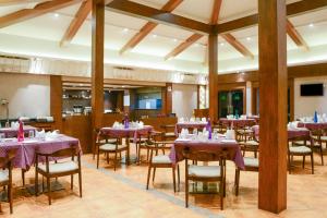 a dining room with purple tables and chairs at Purple Palms Resort & Spa in Kushālnagar