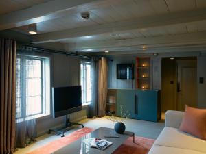 a living room with a couch and a flat screen tv at Tollboden Hotell - Unike Hoteller in Kragerø