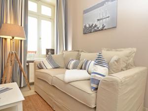 ein Wohnzimmer mit einer weißen Couch mit blauen und weißen Kissen in der Unterkunft Villa Fernsicht - Apt. 06 in Ostseebad Sellin