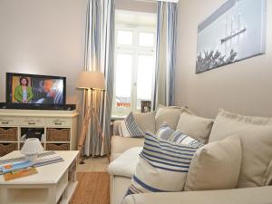 ein Wohnzimmer mit einem weißen Sofa und einem TV in der Unterkunft Villa Fernsicht - Apt. 06 in Ostseebad Sellin