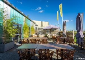 an outdoor patio with tables and chairs and umbrellas at Hotel Libera Spa et Restaurant Caen Colombelles in Caen
