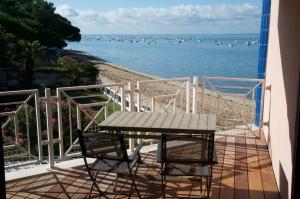 una mesa y sillas en un balcón con vistas al agua en Appartandernos, en Andernos-les-Bains