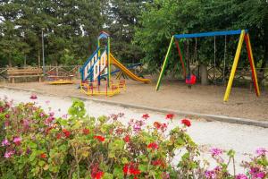 a playground with two swings and flowers in a park at Sicily Country House & Beach in Catania
