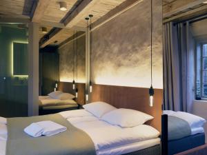 1 dormitorio con 2 camas y almohadas blancas en Tollboden Hotell - Unike Hoteller en Kragerø