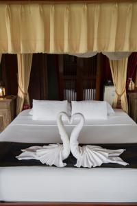 a bed with two towels in the shape of a heart at Shangri-Lao Resort in Luang Prabang