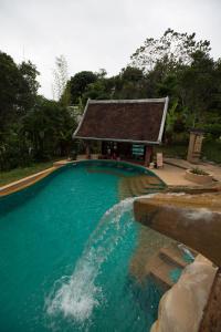 a swimming pool with a building in the background at Shangri-Lao Resort in Luang Prabang