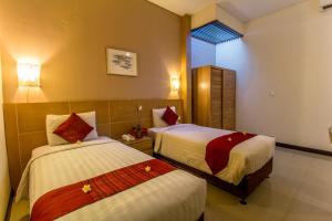 a hotel room with two beds and a window at Svarna Suites Seminyak in Seminyak