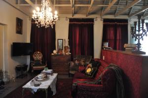 a living room with red curtains and a chandelier at Festina Lente Guesthouse in Johannesburg