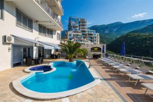 a swimming pool with lounge chairs and a building at Montelux Apartments in Budva