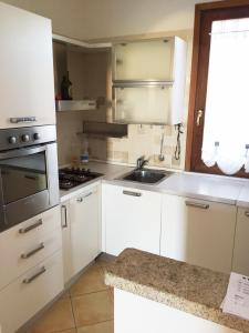 アルツァケーナにあるAppartamento ad Arzachenaの白いキャビネットとシンク付きのキッチン