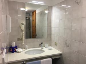 ein Bad mit einem Waschbecken, einem Spiegel und einem Telefon in der Unterkunft B&B Monte Giove Formazza in Formazza