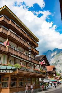 a hotel in the mountains with people walking in front of it at Ferienwohnung Hirschen in Grindelwald