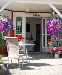 um pátio com uma mesa, cadeiras e flores em Topcamp Bie - Grimstad em Grimstad