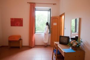 a woman standing in a room looking out a window at Hotel Moderno in Guardia Piemontese Terme