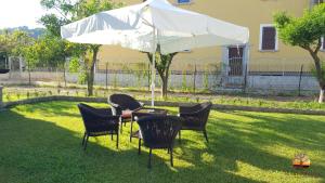 un tavolo e sedie sotto un ombrellone nell'erba di La Chianarella ad Ascea