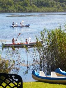 
three people are paddling in a row boat on a lake at Serendipity Country House & Restaurant in Wilderness
