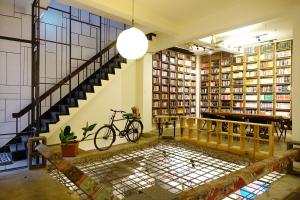 a room with a staircase and a bike in a library at Cao Ji Book Inn Hostel in Tainan